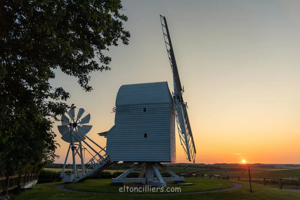 A side on view of Great Chishill Windmill at sunrise with the sun setting over the horizon