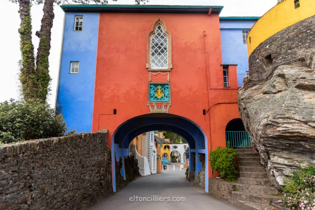 A building painted a dark orange and blue. it has a walkway arch through it