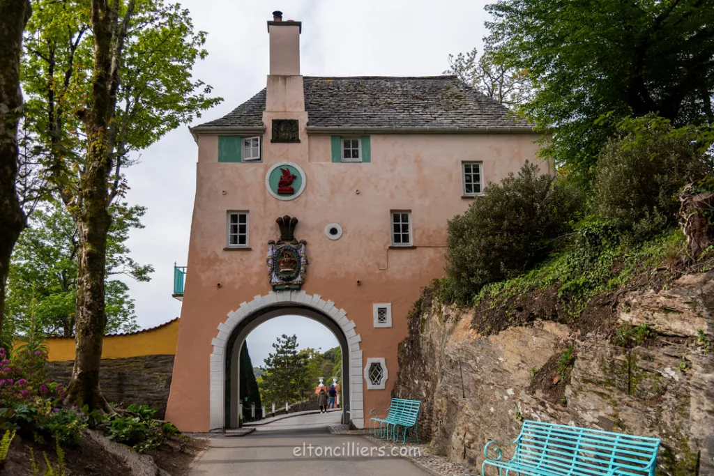 One of the buildings in Portmeirion. Its a salmon pink colour with and arched walkway going under the upper floors. Visitors need to walk though the arch and under the house to get to the main area of the village.