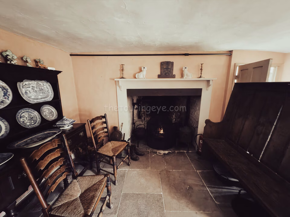 The living room within Hardy's cottage showing the fireplace and basic seating. The Touring Eye. UK History. National Trust. Van Life UK